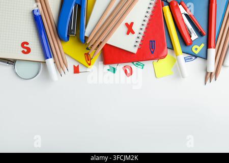 Verschiedene Schulschreibwaren und eine Lupe auf weißem Hintergrund, flacher Lay. Platz für Text Stockfoto