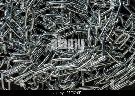 Verwirrte Chrom-Stahlkette als Top-Down-Texturhintergrund. Blick von oben auf einen verwirrten Haufen glänzender metallischer Chromketten, der komplexe industrielle Muster erzeugt Stockfoto