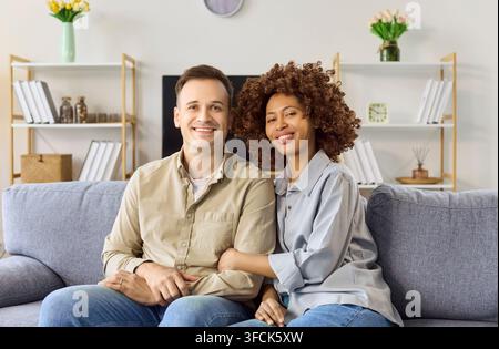 Liebesporträt, das zu Hause auf dem Sofa sitzt, lächelt und sich glücklich fühlt Stockfoto