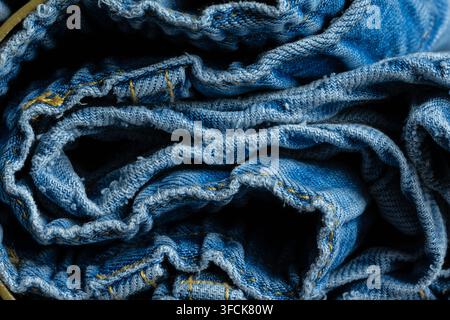 Gerollter blauer Denimstoff, der die Textur und Nähdetails zeigt Stockfoto