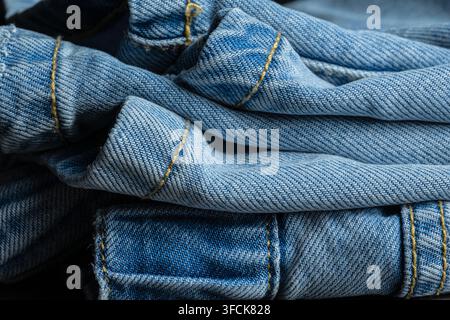 Blauer Denimstoff mit Texturdetails und gelben Nähten als Nahaufnahme-Hintergrund Stockfoto