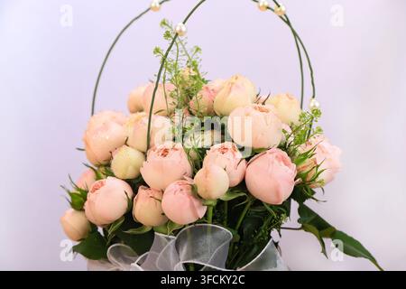 Nahaufnahme eines wunderschönen Straußes aus champagnerfarbenen Rosen mit Tautropfen auf den Blütenblättern. Verziert mit Perlen und zarten Ranken, ist das Arrangement eingefangen Stockfoto