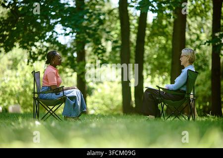 Schwarze Frau hat eine Outdoor-Psychotherapie-Sitzung mit einem Senior-Therapeuten Stockfoto