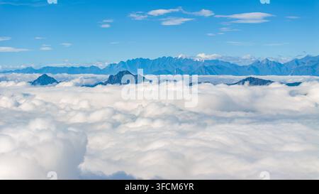 Panoramakonzepte von schneebedeckten Berggipfeln, die unter einem klaren blauen Himmel über einem spektakulären Meer von Wolken aufragen, gesehen vom Niubei-Berg in Sichuan Stockfoto