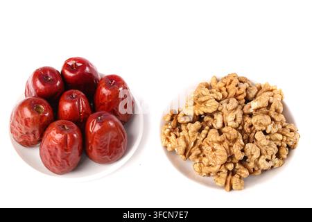 Rote Datteln und Walnusskerne auf weißem Hintergrund arrangiert. Stockfoto