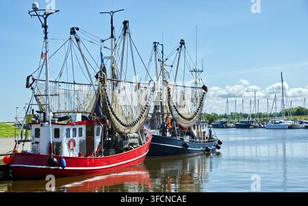 Fischboote mit Garnetzen, die in einem ruhigen Hafen vor Anker liegen, repräsentieren die Nordsee-Tradition und den maritimen Lebensstil unter einem blauen Himmel Stockfoto