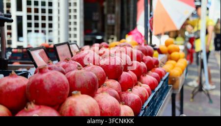 Granatäpfel und Orangen, die auf einem Marktstand im Freien zum Verkauf angeboten werden, Punica granatum-Frucht auf dem Stand, gesunder Lebensmitteleinzelhandel, kommerzieller Lebensmittelladen-Hintergrund Stockfoto