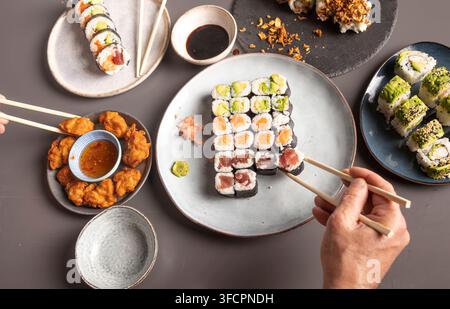 Menschen, die Sushi und japanisches gebratenes Hühnchen zum Abendessen genießen Stockfoto