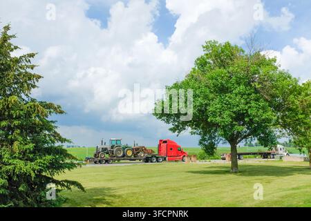 Roter Sattelschlepper, der einen großen Traktor auf einem Anhänger transportiert Stockfoto