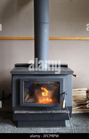 Gemütliches Feuer brennt in einem schwarzen Holzofen Stockfoto