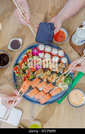Freunde essen ein großes Tablett mit verschiedenen Sushi-Rollen Stockfoto
