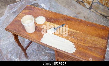 Ein altes Holztablett mit einem Pinsel und einem Topf weißer Farbe streichen, Renovieren und Upcycling Stockfoto