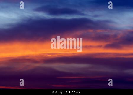 Blick auf einen lebhaften Sonnenuntergang mit intensiven orangefarbenen und roten Wolken, die sich von einem tiefblauen Himmel in Jahanian, Punjab, Pakistan abheben. Stockfoto