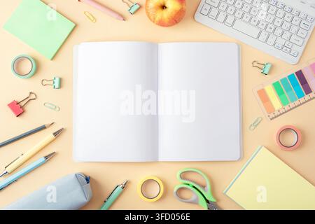 Pastellfarbene Schreibwaren um ein offenes Notizbuch auf einem beigefarbenen Schreibtisch arrangiert, mit Bleistiften, Stiften, Computertastatur, Schere und farbenfrohen Büromaterialien Stockfoto