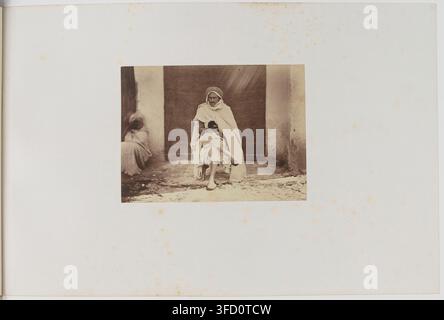 Eine Frau und ein Kind sitzen auf einer Türschwelle, mit einer weiteren teilweise sichtbaren Figur hinter ihnen, in einer Fotografie von Félix-Jacques-Antoine Moulin, einem französischen Fotografen, aufgenommen in der Provinz Algier, Algerien, zwischen 1856 und 1857. Stockfoto