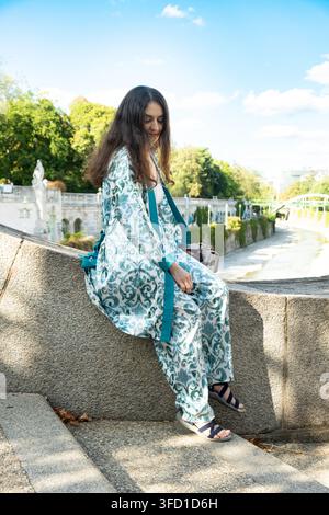 Schöne erwachsene brünette Frau sitzt im Stadtpark im Freien. Stockfoto