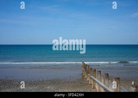 Wellen an einem Strand unter einem blauen Himmel und Meeresbrandung Stockfoto