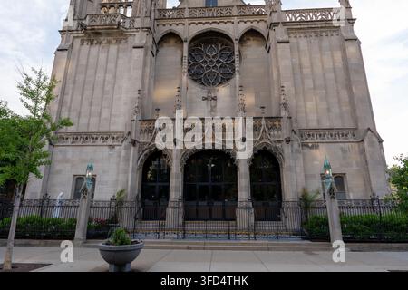 Vorderansicht einer historischen neogotischen Kirchenfassade mit einem großen runden Rosettenfenster, spitzen Bögen, dekorativem Steinmetzwerk und schmiedeeisernem Zaun Stockfoto