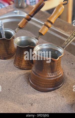 Türkischen Kaffee in traditionellen Töpfen auf Sand brauen Stockfoto