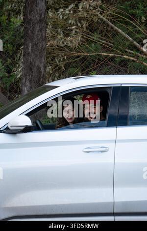 Seitenansicht eines glücklichen Paares, das auf einer Outdoor-Roadtrip in einem weißen Volkswagen Limousine fährt Stockfoto