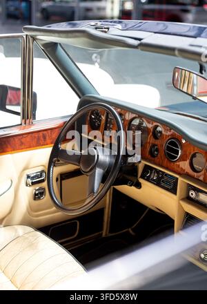 Ansicht in ein luxuriöses Vintage-Cabriolet mit beigen Ledersitzen, schwarzem Lenkrad, einer reich verzierten polierten Holzarmatur und Chrom-Akzenten. Stockfoto