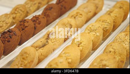 Financiers mit Mandel- und Schokoladenbelag in Reihen auf einem Tablett, Backwarenladen-Umgebung, Tortenpräsentation für gewerbliche Nutzung. Stockfoto