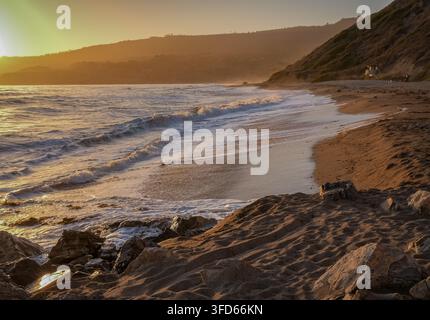 Goldenes Sonnenlicht erhellt Wellen, die entlang eines felsigen Strandes an der Küste Kaliforniens brechen. Stockfoto
