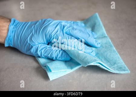 Schmutz mit einem Tuch abwischen, während Schutzhandschuhe getragen werden. Stockfoto