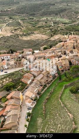 Luftbild eines kleinen Dorfes mit Terracotta-Dächern in der Nähe von Margalef, Katalonien, Spanien, eingebettet zwischen grünen Hügeln und Olivenbäumen. Eine charmante ländliche Siedlung Stockfoto
