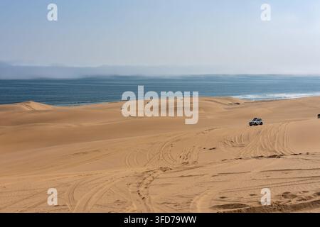 Ein Geländewagen fährt auf Sanddünen entlang der Atlantikküste in Sandwich Harbour, Namibia. Stockfoto