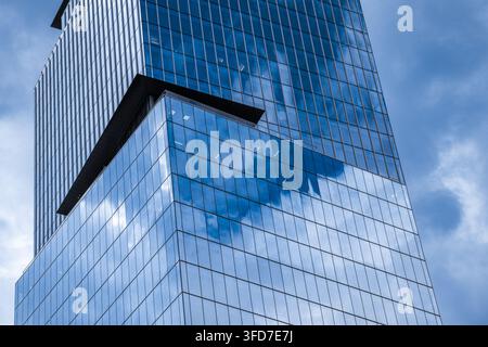 Der Stack-Wolkenkratzer mit gedrehten Glasbüroblöcken, die den blauen Himmel und die Wolken im Zentrum von Vancouver, British Columbia, reflektieren. Stockfoto