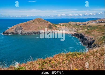 Weite Sommeraussicht auf den belebten Mwnt-Strand und dramatische Klippen in Ceredigion Wales unter einem lebendigen blauen Himmel Stockfoto