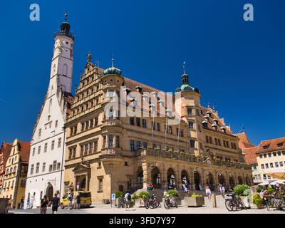 Rothenburg, Deutschland – 03. Jul 2026: Sonnige Ansicht des historischen Rathauses in Rothenburg mit kunstvoller Architektur, Touristen und Fahrrädern auf dem alten Marktplatz Stockfoto