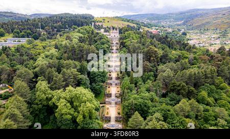 Lamego Portugal, Luftaufnahme eines langen, geraden Weges, der sich durch einen üppigen grünen Wald schneidet. Der Weg führt zu einer entfernten burgenähnlichen Struktur auf einem Hügel. Bäume Stockfoto