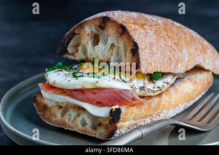 Frischer Lachs, Ei-Sandwich, Nahaufnahme. Gesalzener Lachs, Spiegelei, Butter und Weißbrot auf dem Teller Stockfoto