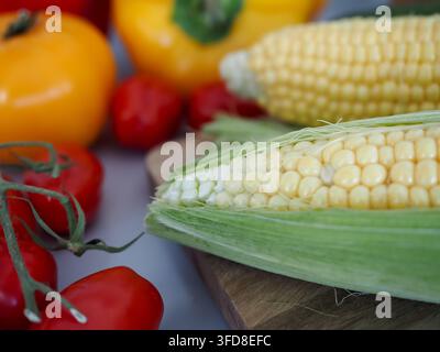 Bunte Mischung aus Gemüse inklusive Mais, Tomaten und Paprika in einer Küchenszene zu Hause Stockfoto