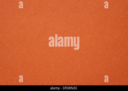 Orange Papiertextur, die ein lebendiges, körniges und erdiges Hintergrundmaterial bietet Stockfoto