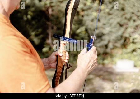 Person, die ein T-Lineal zur präzisen Anpassung der Bogensehne während des Bogenschießen-Trainings verwendet Stockfoto