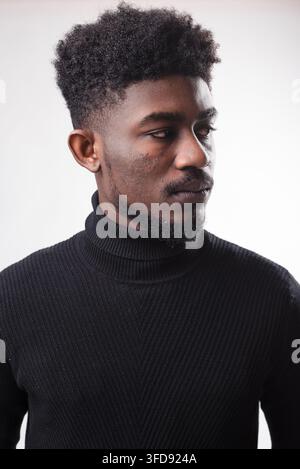 Ein Nahaufnahme-Studio-Porträt eines jungen schwarzen Mannes mit einer texturierten Afro-Frisur und einem Bart, der zur Seite schaut Stockfoto