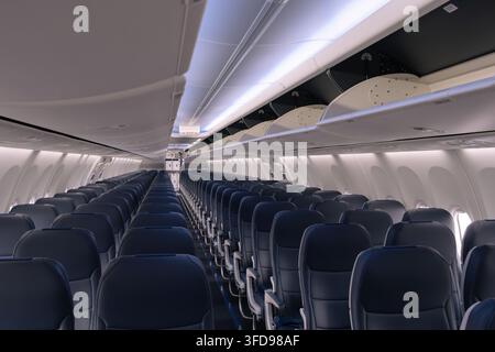 Leere Economy-Class-Kabine einer Boeing 737 MAX 8 mit blauen Sitzen und offenen Gepäckfächern Stockfoto