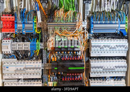 Eine detaillierte Ansicht eines modernen industriellen elektrischen Steuergeräts mit vielen farbenfrohen Kabeln, Leistungsschaltern und Klemmblöcken Stockfoto
