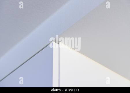 Abstrakte Ansicht einer Ecke, an der zwei Wände aufeinandertreffen, mit klaren Linien, geometrischen Formen und sanftem Licht für einen zeitgenössischen Look Stockfoto
