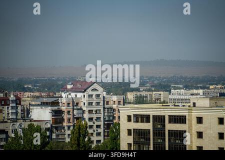 Eine Luftaufnahme von Almaty zeigt eine Mischung aus Wohngebäuden, darunter ein auffälliges weißes Gebäude mit einem markanten rotvioletten Dach und einem Bogen Stockfoto