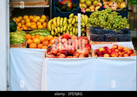 Ein Foto, das eine üppige Marktauslage mit frischen saisonalen Früchten zeigt, darunter Pfirsiche, Nektarinen, Bananen, Trauben, Wassermelonen, Orangen, Zitronen Stockfoto