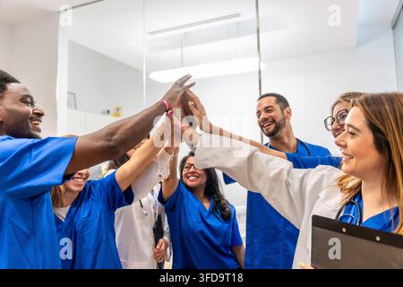 Verschiedene Mitglieder des medizinischen Teams geben sich High Fives und feiern den Erfolg der Teamarbeit Stockfoto