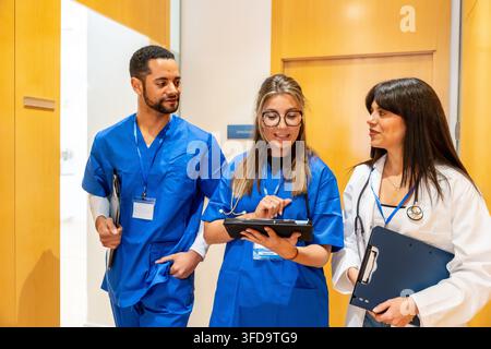 Medizinisches Team, das im Krankenhausflur zusammenarbeitet und Patientendaten bespricht Stockfoto