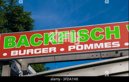 HAMBURG, DEUTSCHLAND - 26. AUGUST 2026 - Rotes Straßenessenschild, das traditionellen deutschen Backfisch, Burger und Pommes anbietet, vor einem blauen Himmel Stockfoto