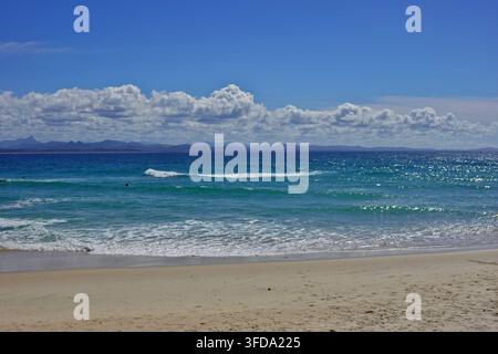 Kleine Wellen, die an einem sonnigen Tag auf einem Sandstrand brechen Stockfoto