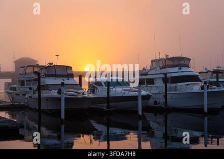 New Bern North Carolina - 19. Januar 2023: Boote im Hafen während eines nebligen Sonnenaufgangs in New Bern North Carolina Stockfoto