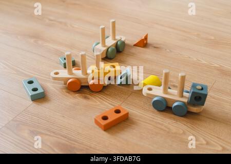 Holzspielzeugautos umgeben von bunten Blöcken auf einem Naturboden, die eine spielerische Umgebung für die Kreativität der Kinder schaffen. Stockfoto